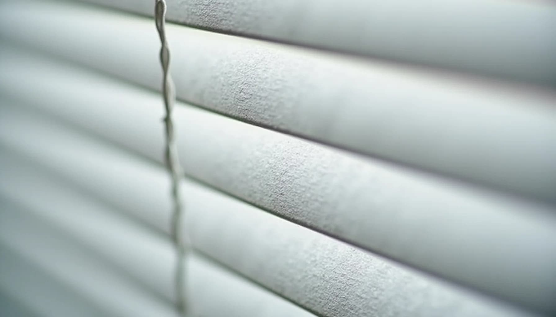 horizontal white fabric blinds with a twisted control cord running vertically along the slats