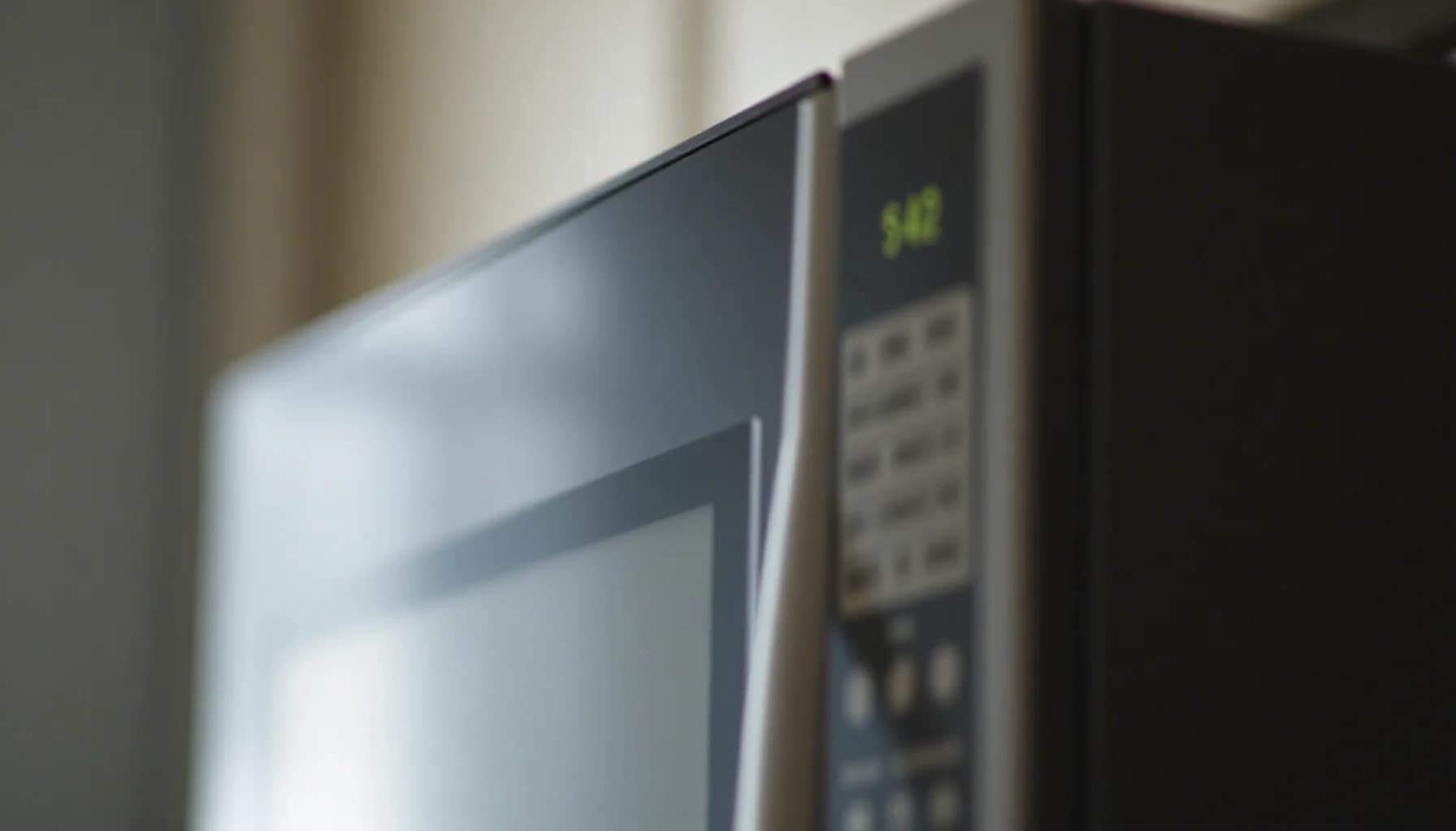 Microwave oven with digital display showing time and control buttons on beige wall background