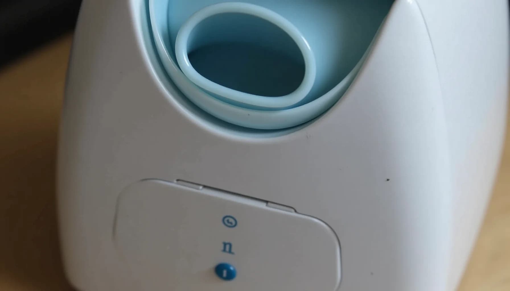 White humidifier with teal outlet opening and blue control buttons on wooden surface