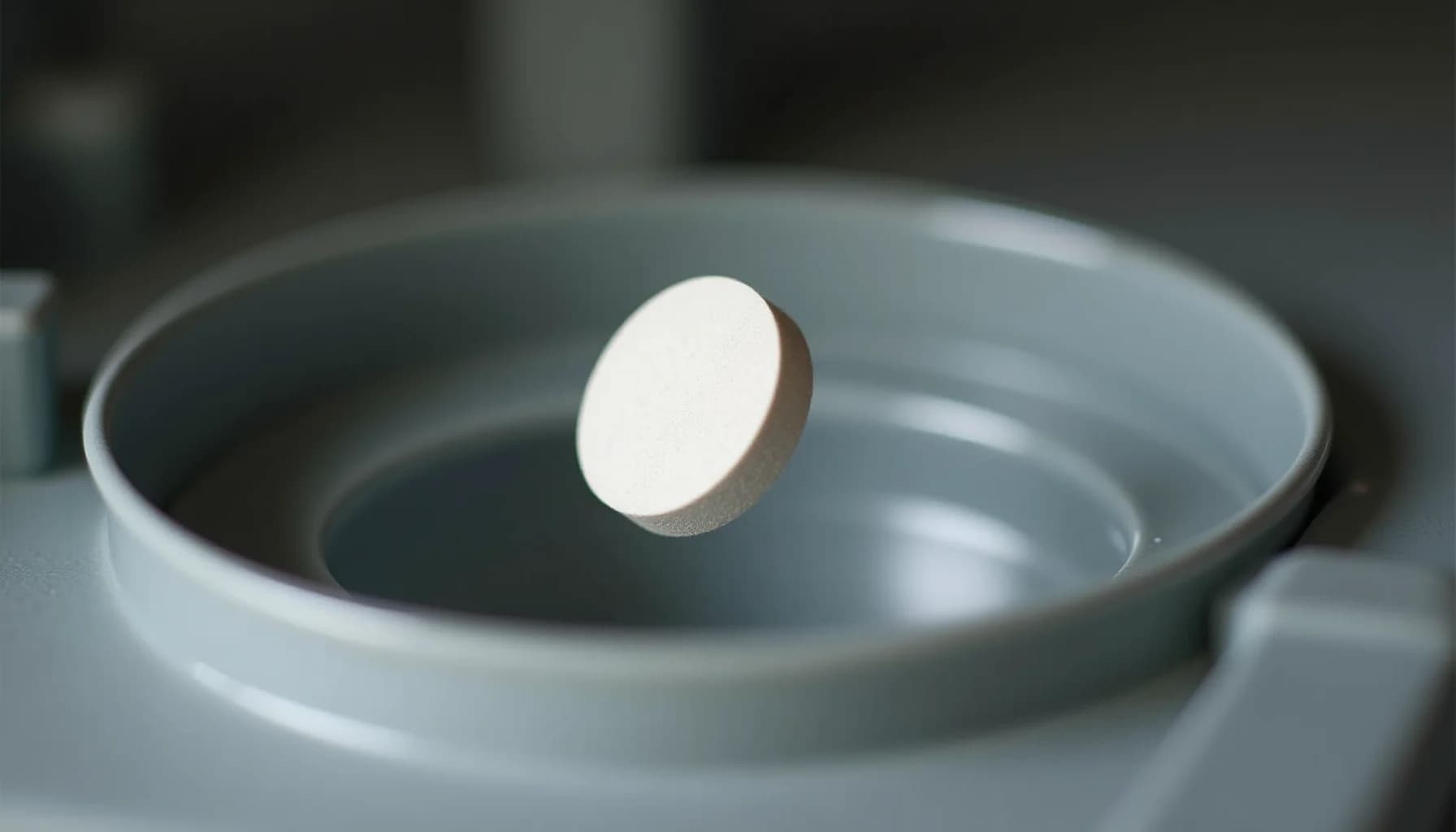 White tablet resting in gray dishwasher basin filled with water, showing cleaning product for maintenance
