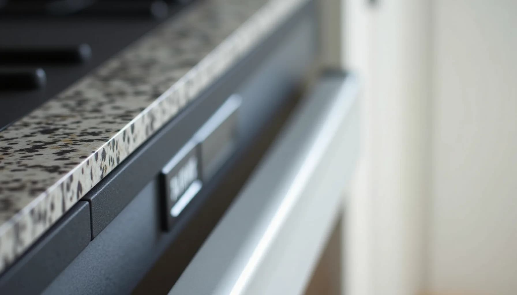 kitchen countertop edge with speckled surface and built-in appliance handle, shot at an angle
