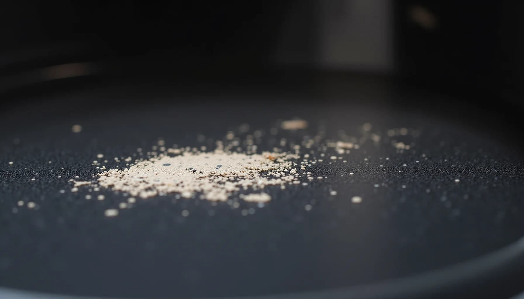 White and beige granular powder scattered across a dark textured surface